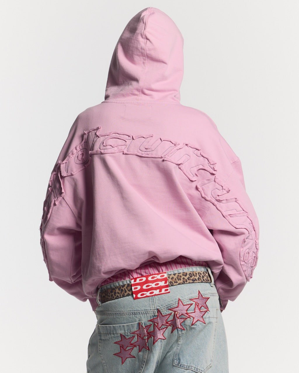 DISTRESS CURVED HOODIE PINK - pink distressed hoodie, back view on female model - Cold Culture #woman