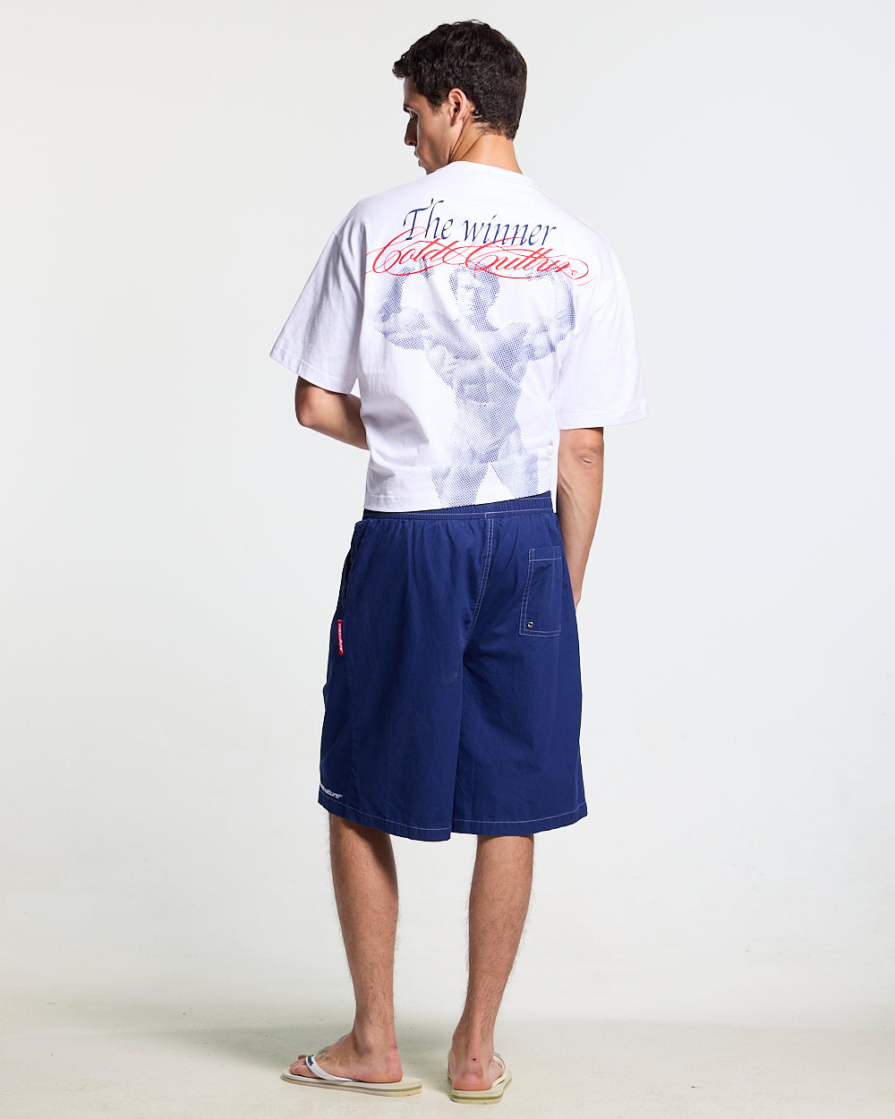 CROSSED SWIMSHORTS BLUE - navy gothic print swim shorts, back view on male model - Cold Culture #man