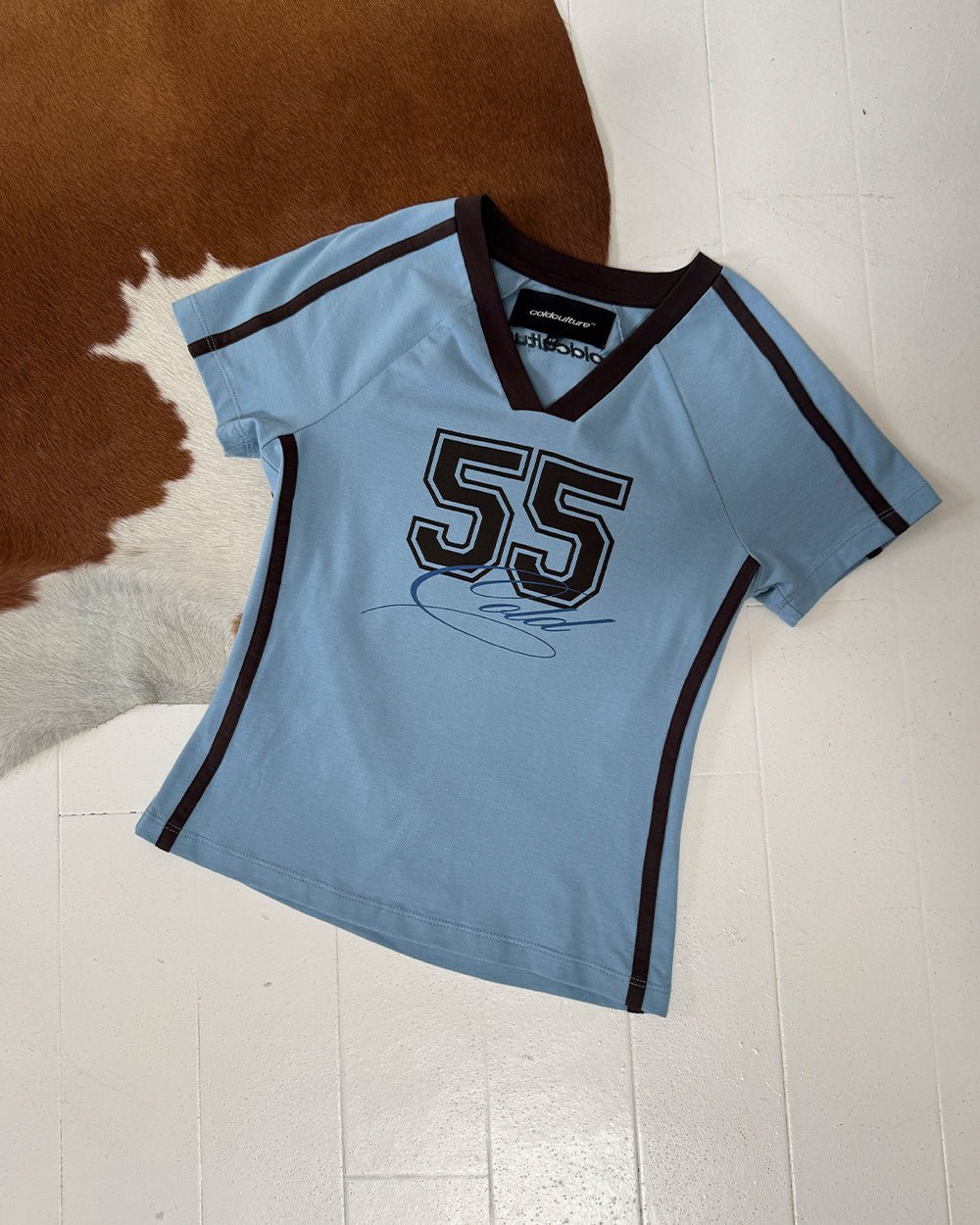 BANDAL BABY TEE BLUE - light blue varsity baby tee, flat lay - Cold Culture