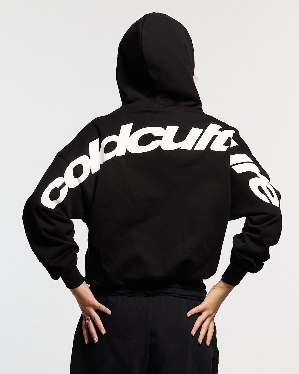 CURVED HOODIE BLACK AND WHITE - black oversized hoodie, back view on female model - Cold Culture #woman