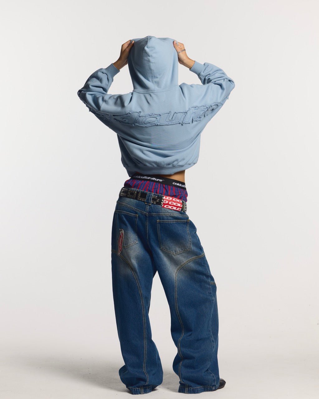 DISTRESS CURVED HOODIE SHADY BLUE - light blue distressed hoodie, back view on female model - Cold Culture #woman