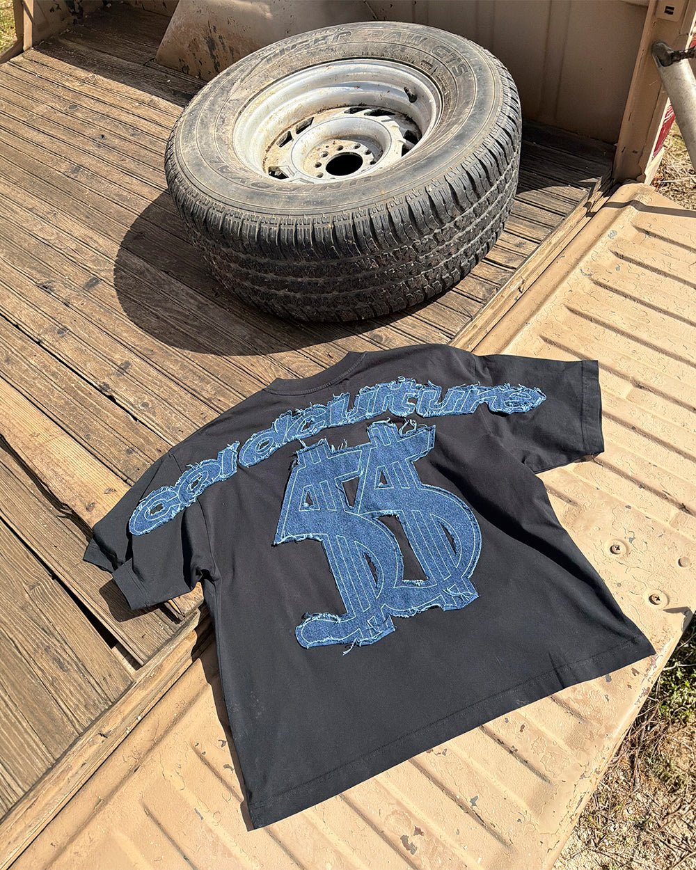 DISTRESSED DOLLAR TEE BLACK - black tee with denim applique, flat lay - Cold Culture