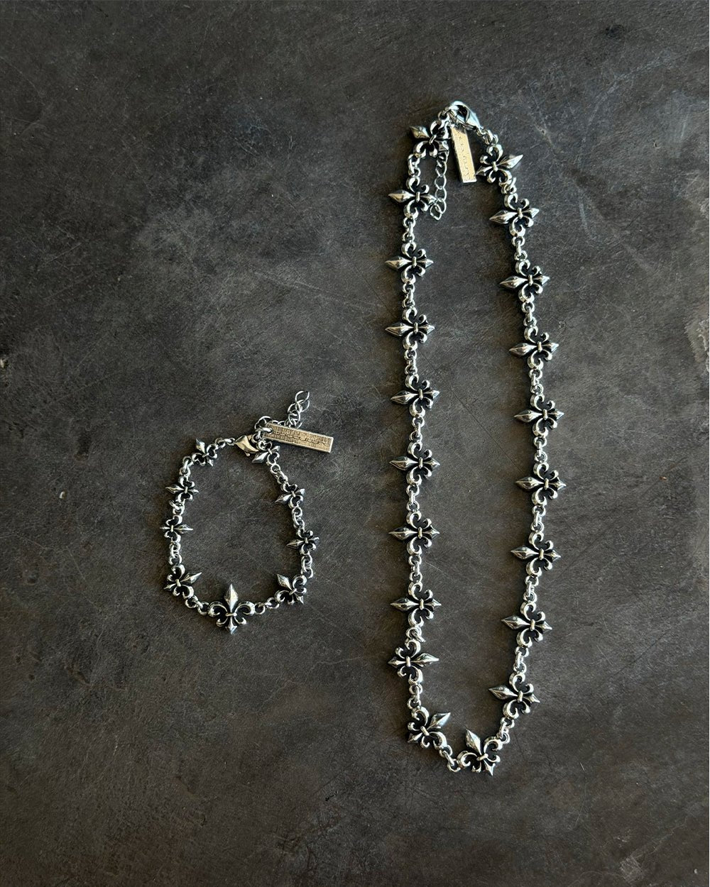 LOOSE ICON BRACELET SILVER - silver fleur-de-lis chain bracelet, flat lay with matching pieces - Cold Culture