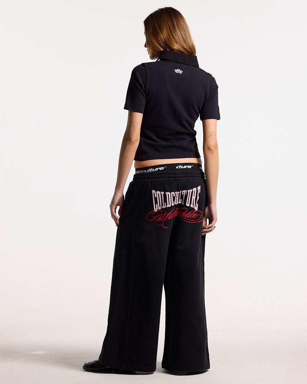 NIA SET POLO BLACK - black graphic print polo shirt, back view on female model - Cold Culture #woman