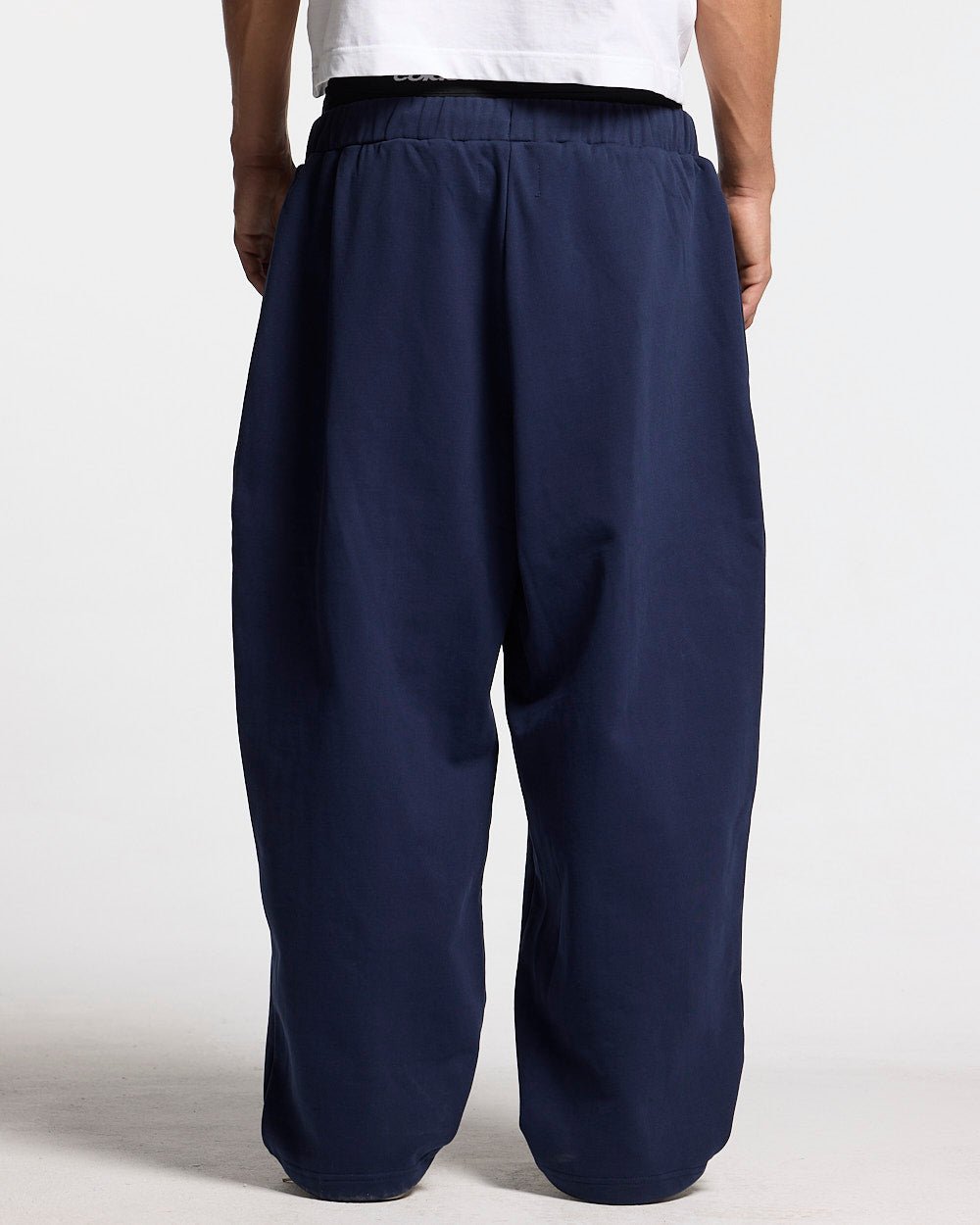VARSITY PANTS DARK BLUE - navy blue baggy sweatpants, back view on male model - Cold Culture