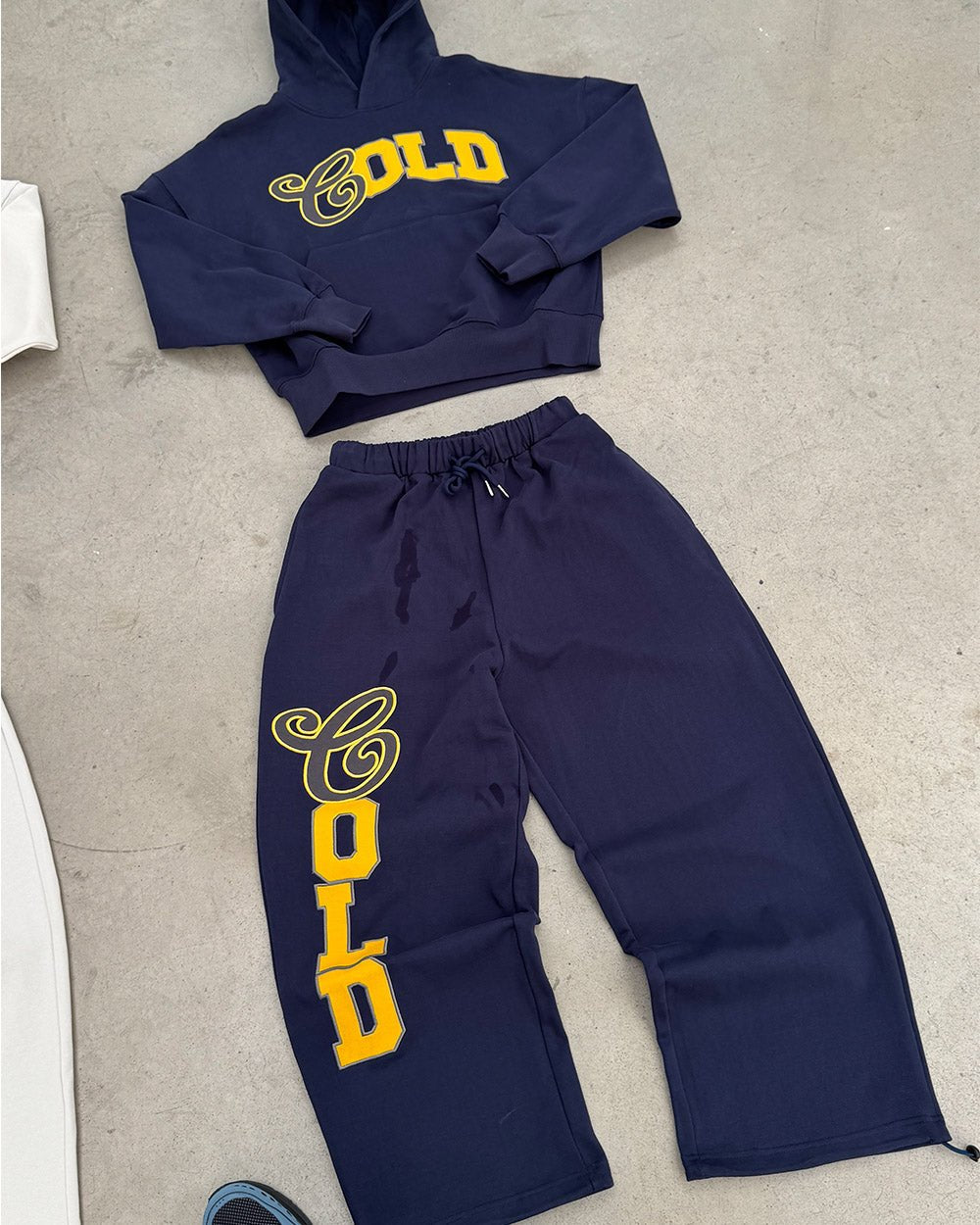 VARSITY PANTS DARK BLUE - navy blue baggy sweatpants, flat lay with matching pieces - Cold Culture